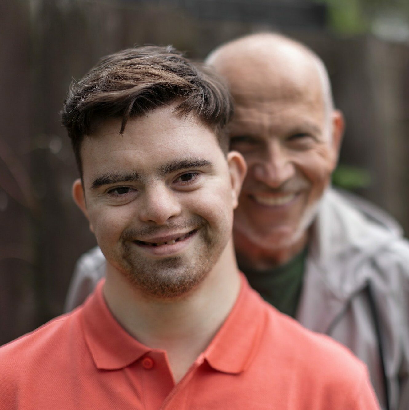 Portrait of happy senior father with his young son with Down syndrome outdoors.